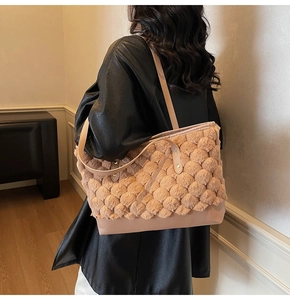 Detailed view of apricot plush ball texture and smooth leather strap on tote bag