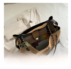 Spacious tan suede shoulder bag with black trim and chain strap showing interior capacity