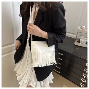 Detailed view of white crossbody bag featuring long vertical tassels and a slim strap