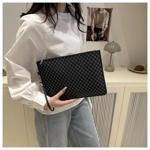 Chic women's clutch bag with geometric pattern held by a model in a minimalist room