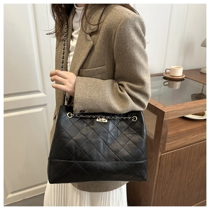 Detail of black quilted leather shoulder bag with gold twist lock and chain strap