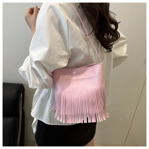 Side view of pink leather shoulder bag with long fringe tassels on a female model