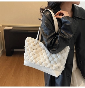 Detail of white woven textured tote bag with smooth leather strap on a black leather coat
