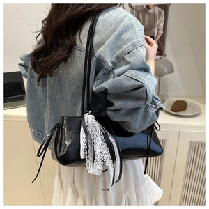 Detailed view of black patent leather underarm bag with white lace bow and side drawstrings