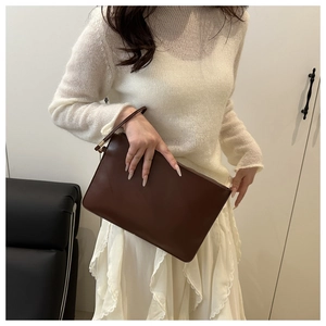 Close-up of a deep brown faux leather wristlet bag with a metallic zipper detail