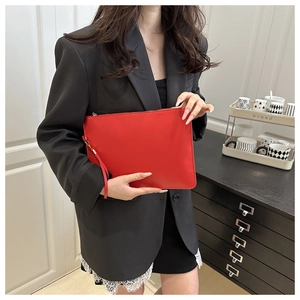 Close-up of a bright red faux leather envelope clutch with a zipper and wristlet strap