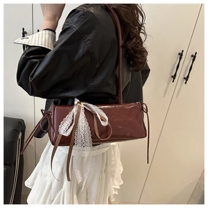 Detail view of the burgundy baguette bag featuring white lace bow and silk ribbon accents