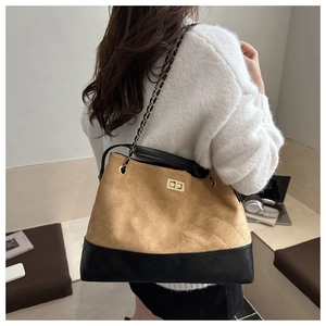 Close-up of quilted bucket bag with chain strap and gold twist lock in minimalist room