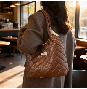 Brown quilted tote bag with fashion label shown on model in a sunlit cafe setting