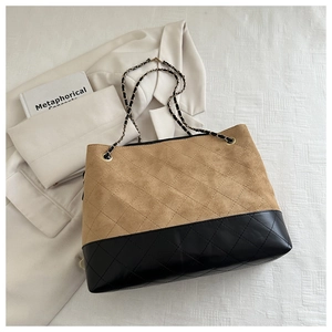 Close-up of khaki and black paneled tote with diamond quilting and chain strap