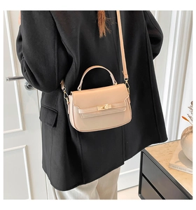 Dettaglio di una borsa a tracolla beige minimalista con chiusura a scatto dorata su modella