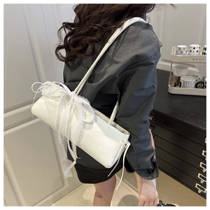Detail of white baguette shoulder bag with elegant lace bow on smooth faux leather finish