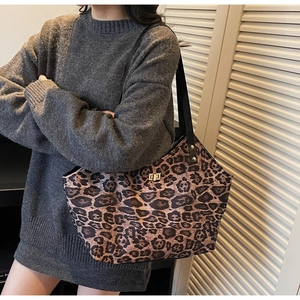 Detail of leopard print tote bag with gold twist lock and black strap on grey sweater