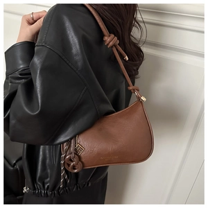 Détail du sac hobo marron vintage avec bandoulière nouée et breloque métallique