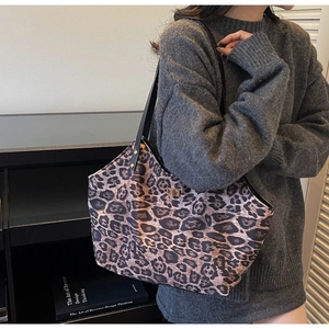 Close-up of leopard print tote bag with metal twist lock worn by a model in casual attire