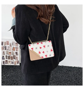 Detail showing printed bear pattern and gold chain strap on stylish crossbody bag