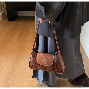 Close-up of brown crocodile pattern shoulder bag with a vintage metal bow decoration