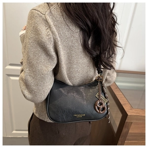 Détail du sac croissant noir plissé avec breloques bretzel et boulier créatifs
