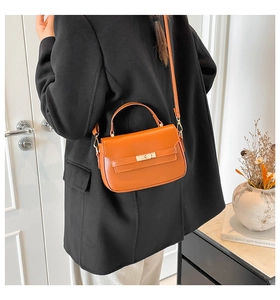 Borsa a mano in pelle marrone arancio con dettaglio cintura indossata da modella