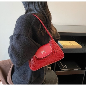 Detail of red crocodile pattern shoulder bag with a stylish silver bow metal buckle