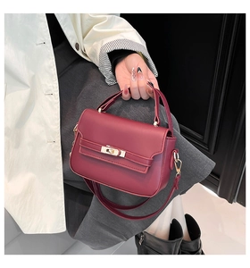 Dettaglio borsa in pelle bordeaux con chiusura a rotazione dorata e tracolla lunga