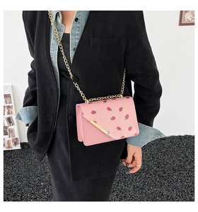 Detail of pink strawberry pattern crossbody bag with gold chain and envelope flap