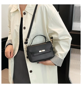 Dettaglio di una borsa a tracolla nera minimalista con fibbia dorata sulla modella