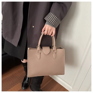 Vista dettagliata di una borsa tote in pelle martellata beige con finiture dorate