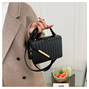 Details der schwarzen Webstruktur an der quadratischen Lederhandtasche mit Metallschnalle