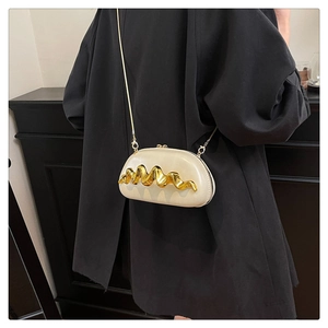 Dettaglio mini borsa beige con barra metallica dorata ondulata e tracolla a catena