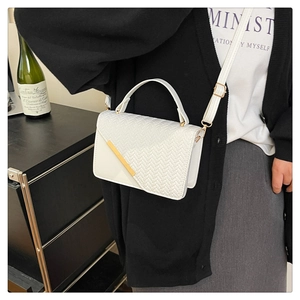 Detail der weißen PU-Lederhandtasche mit gewebter Fischgrätenklappe und Goldmetallbesatz
