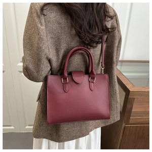 Borsa a mano in pelle PU bordeaux con fibbie dorate indossata da una modella retro