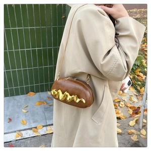 Close-up of brown oval clutch with gold wavy metal trim and slim chain strap