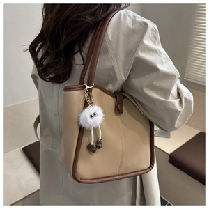 Chic beige and brown minimalist tote bag worn by model with plush doll charm accessory