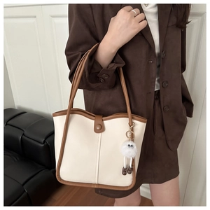Detail of contrast stitching on beige bucket bag with cute plush monster charm
