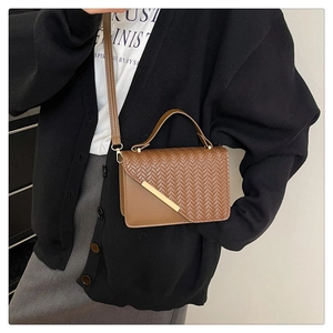 Detail der braunen kleinen Quadrat-Tasche mit Webstruktur und goldenem Metallrand