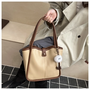 Close-up of minimalist beige and brown tote bag with cute furry ball pendant on wood steps