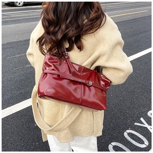 Détail du sac à bandoulière en cuir verni bordeaux brillant avec boucle et sangle