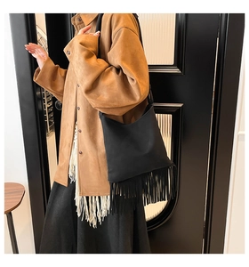 Fashionable black suede shoulder bag with long fringe details in a bohemian style