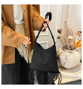 Detail of a black suede Hobo bag with long fringes and thick handle in boho style