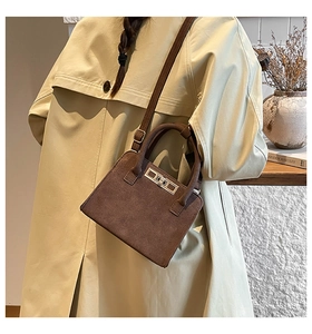 Brown suede crossbody bag worn by a model in a trench coat, showing its elegant fit