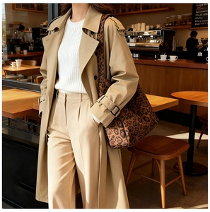 Detail of leopard print tote bag paired with khaki trench coat in a cafe setting