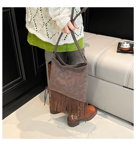Close-up of vintage brown suede shoulder bag featuring long ethnic fringe details