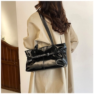Side view of a glossy black patent leather tote bag with stylish buckle and stitching details