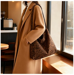 Detailed view of leopard print tote bag on shoulder over a camel wool coat