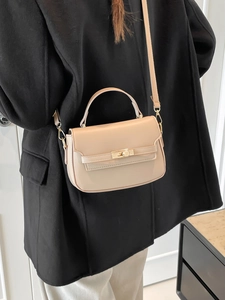 Borsa a tracolla beige minimalista con chiusura a rotazione dorata e manico su blazer nero