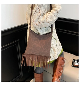 Detail view of deep brown suede crossbody bag with long fringe and adjustable strap