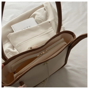 Top view of beige shoulder bag interior featuring brown contrast trim and metal zipper