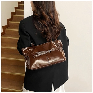 Close-up of vintage dark brown glossy tote bag with metal buckle and shoulder strap