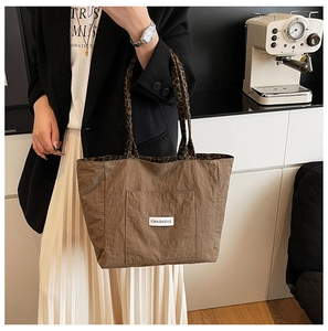 Detail of brown nylon tote bag with leopard print handles and brand label patch